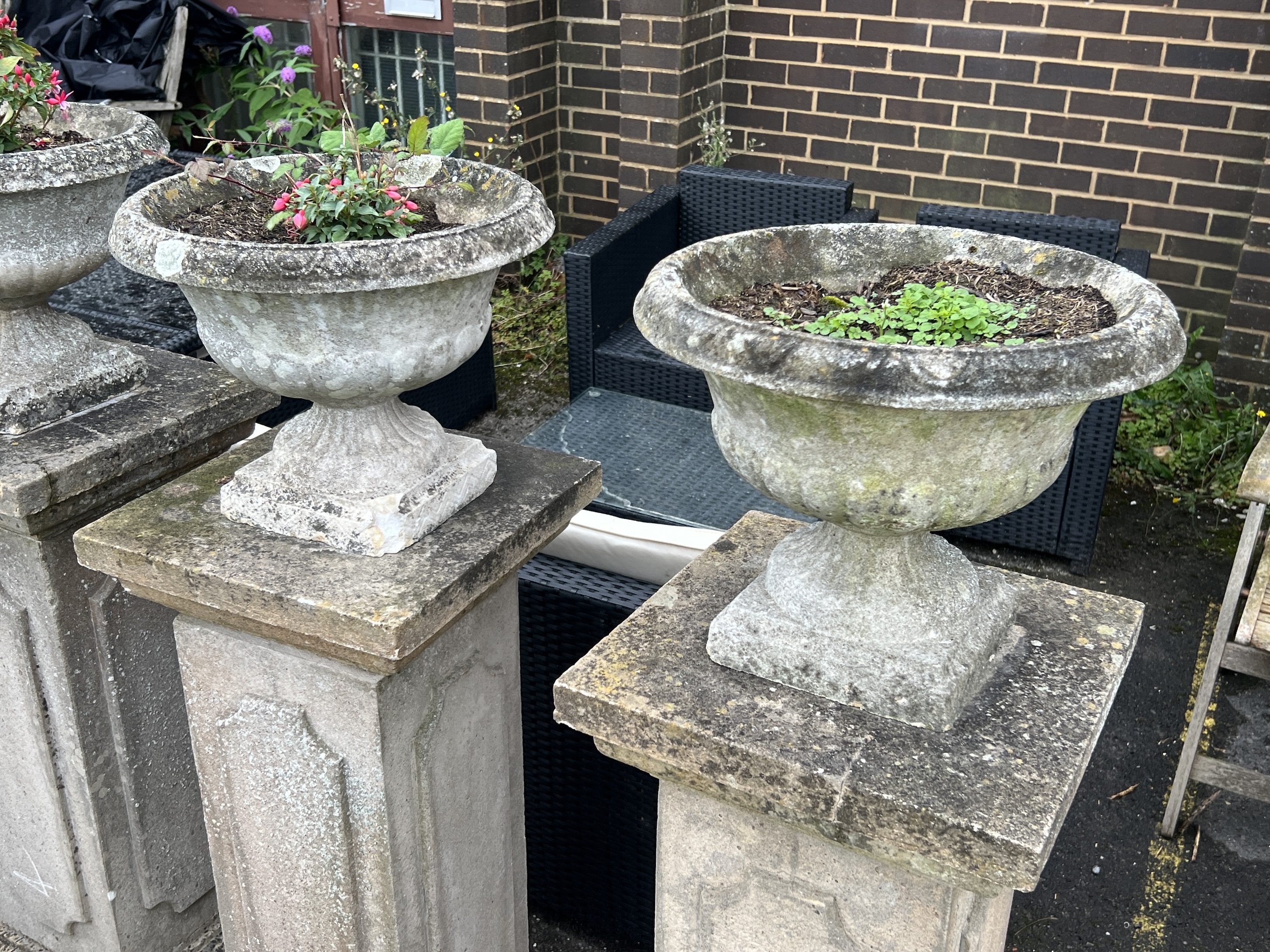 A set of four circular reconstituted stone garden planters on tall square plinths, height 134cm